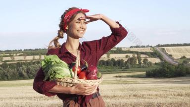 女人农民持有篮子蔬菜洋葱番茄沙拉黄瓜站农田微笑女农学家专家农业农业综合企业漂亮的女孩穿着红色的网纹衬衫大手帕